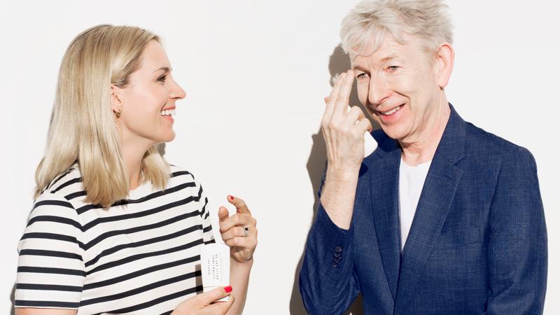 A smiling Beauty Pie team member holds Ultralight Daily SPF 30 sunscreen next to collaborator Dr. Markey, who applies the product to his face.